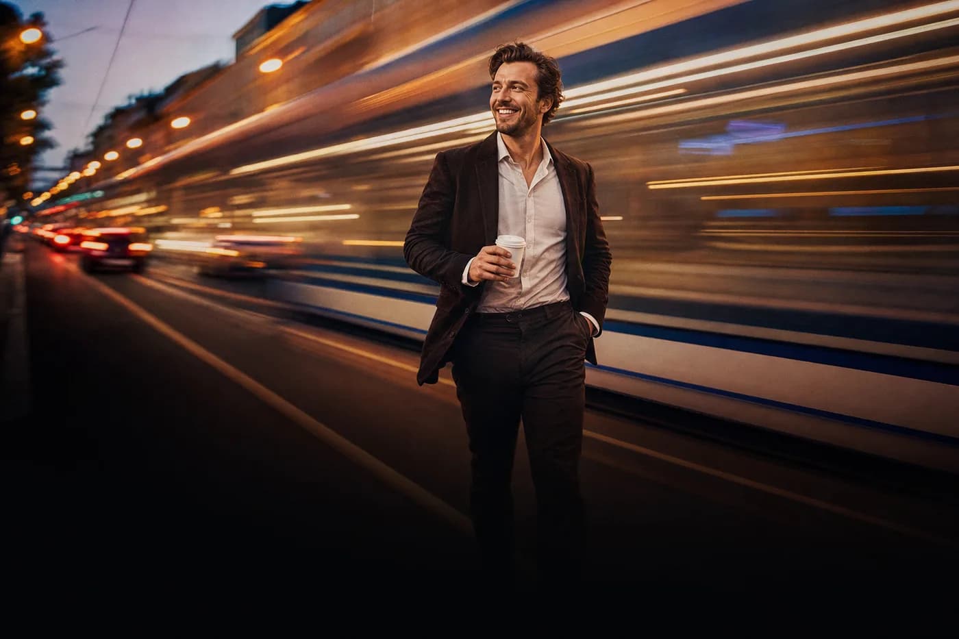 Entspannter Unternehmer schlendert abends mit Kaffee, eine Tram zieht Lichtstreifen hinter ihm